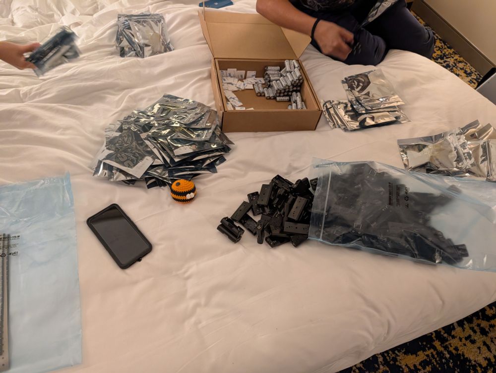 A hotel bed with various kit components in piles ready for assembly 