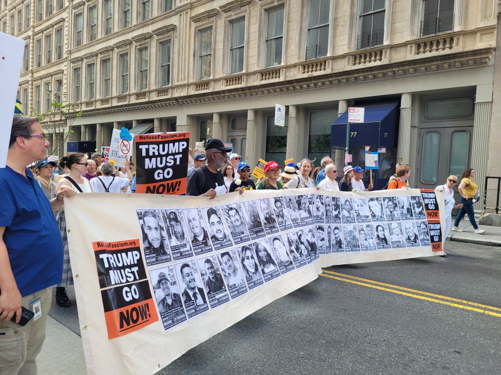 Protestors at Good Trouble Lives On march in lower Manhattan with banner showing victims of ICE.