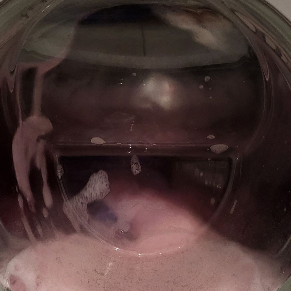 Waschmaschine gefüllt mit Wäsche. Der Schaum ist pink.