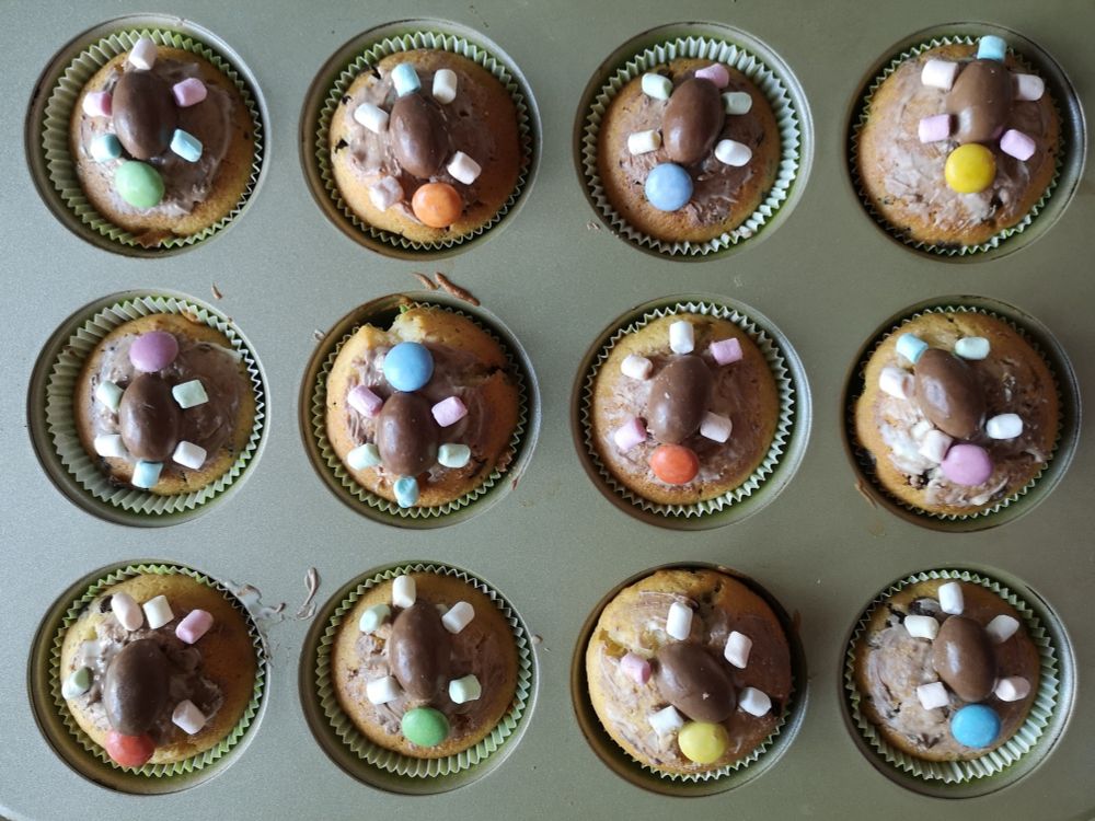 Muffins mit Schokoglasur, darauf je eine kleine Schildkröte aus einem halben Schokobonbon als Panzer, einem Smartie als Kopf und fünf Minimarshmallows als Beine und Schwanz.