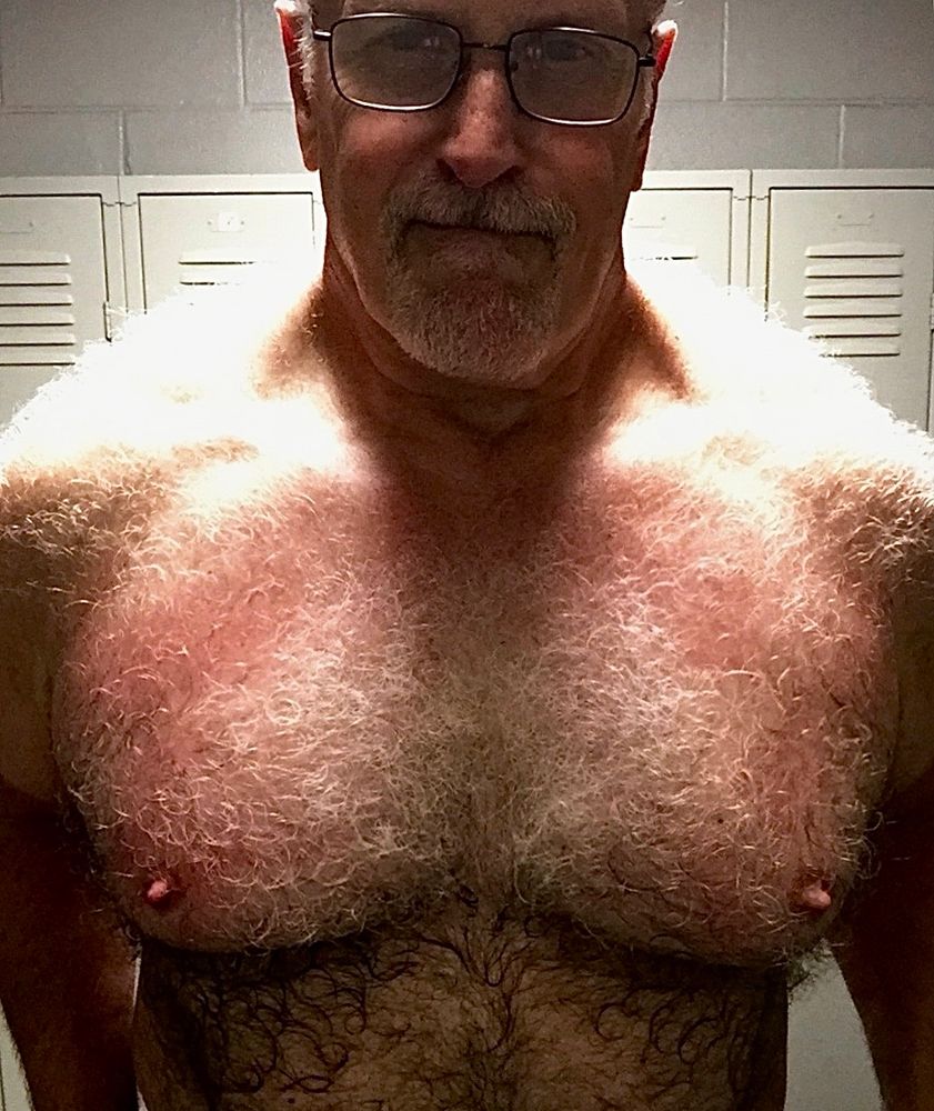 Standing bare chested before a locker.