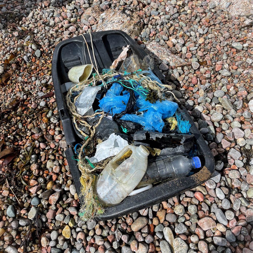 A black plastic sled filled with plastic waste - bottles, ropes etc