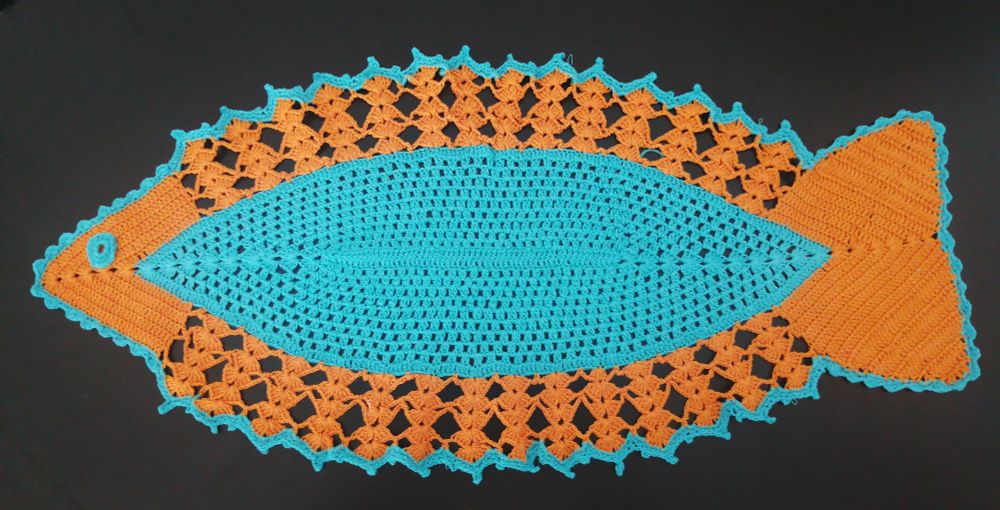 Hand made table doily, shaped like a fish, orange and blue 