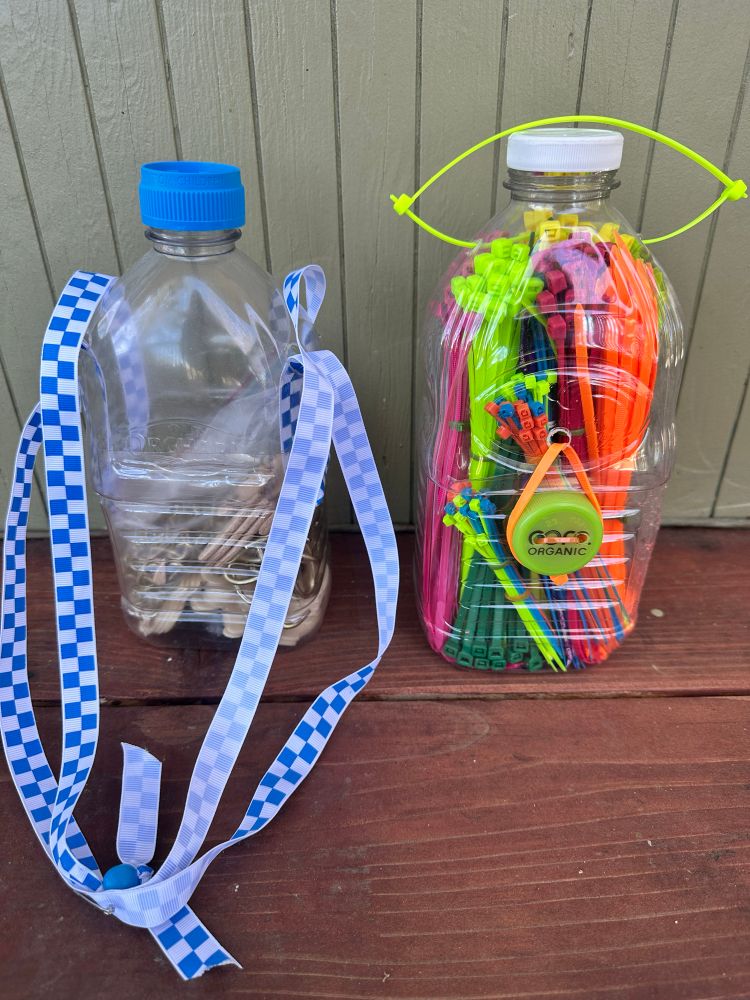Bottle on left has holes punched for ribbon handles, that make the lid slide up the ribbon to access the tools. Bottle on right opens and closes with a “button” type fastener made from a pierced bottle cap and small zip ties. 