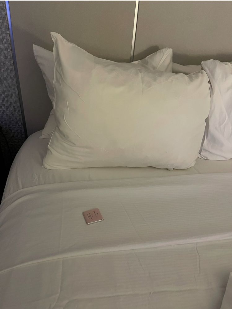 A picture of hotel bed with a wrapped chocolate left on the bed after turndown service. 