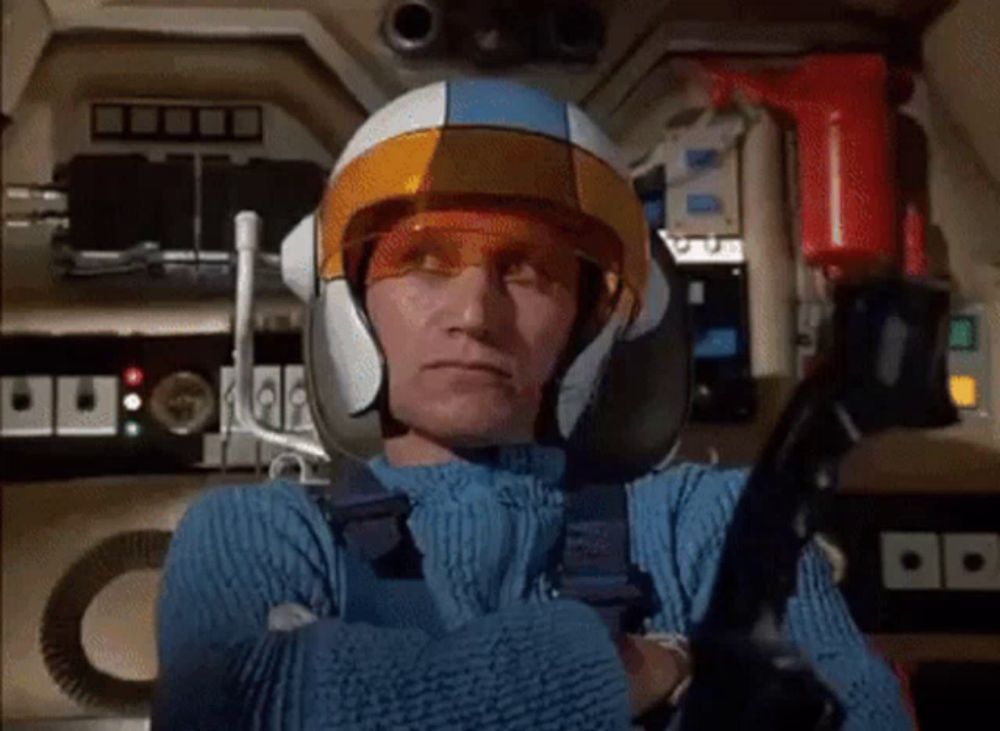 a man wearing a blue sweater and a helmet is holding a steering wheel