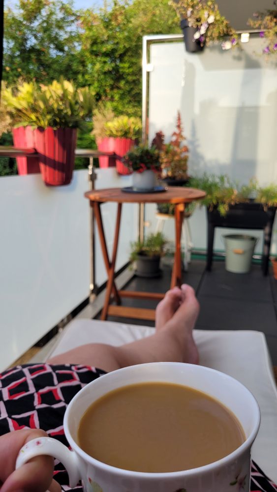 Kaffetasse wird auf dem Balkon ins Bild gehalten. 