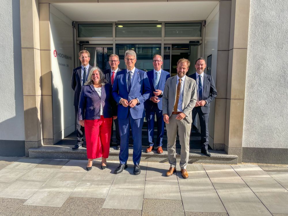 Gruppenfoto in Hamburg vor dem Gebäude der Hamburger Hochbahn. Mittig steht Verkehrsminister Patrick Schnieder, links neben ihm steht Heidi Alexander, die britische Verkehrsministerin. Rechts von Patrick Schnieder steht der Hamburger Verkehrssenator Anjes Tjarks. 