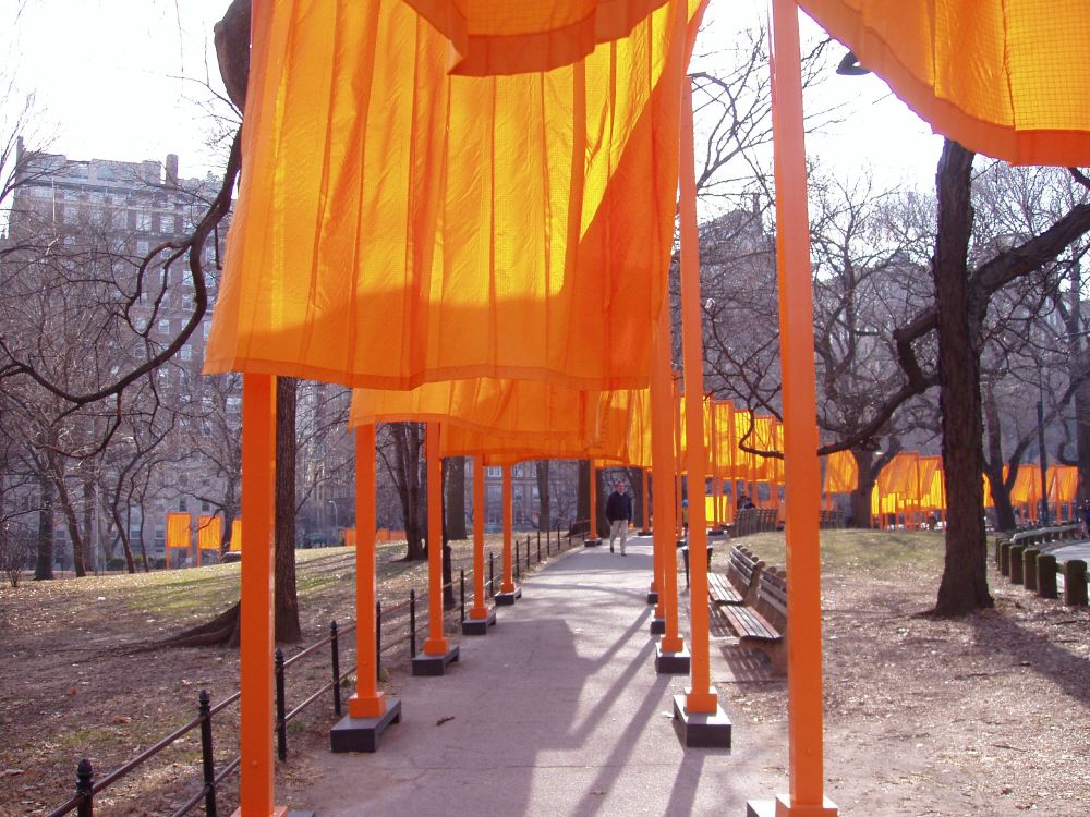 Saffron gates with beams hang in a row along the pathways of Central park with the sun shining through