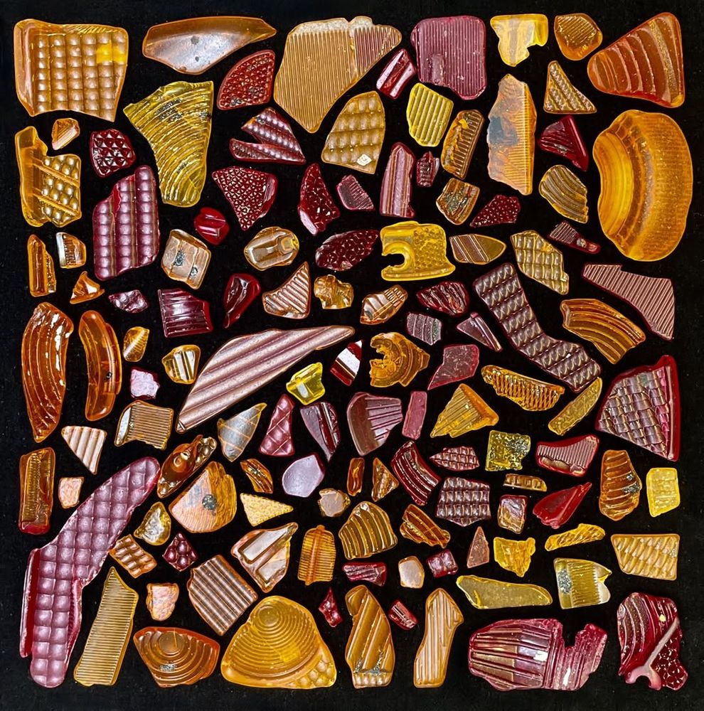Shards of red and orange plastic 'glass' laid out on a black background.