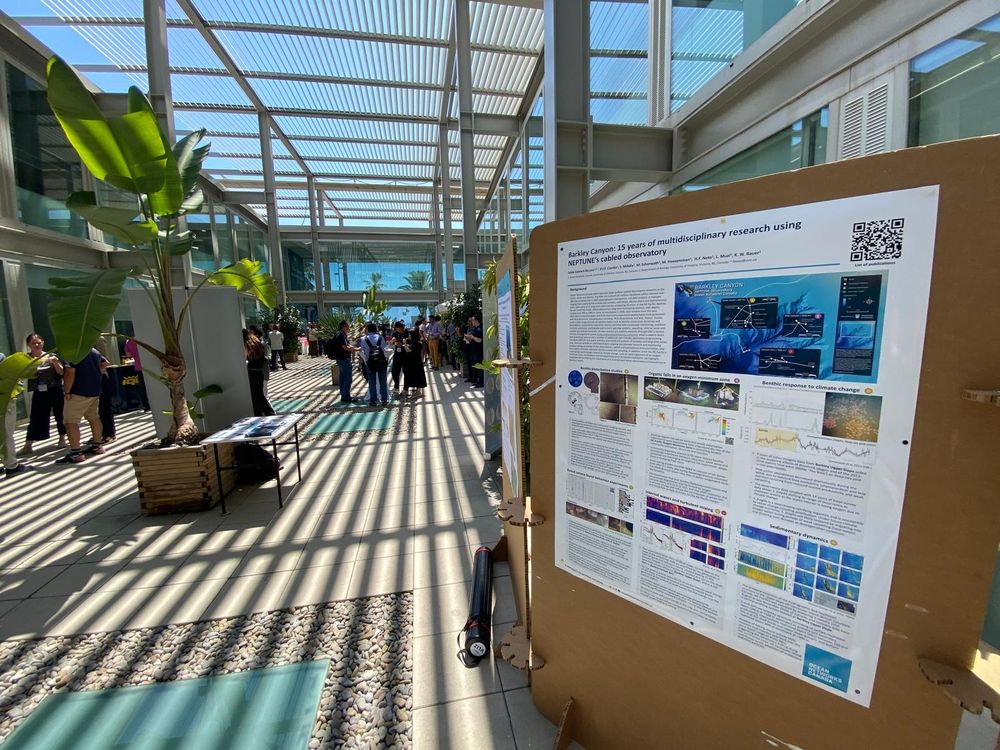 Poster presentation on Barkley Canyon research displayed in a sunlit atrium at the INCISE symposium, with attendees gathered in the background.

