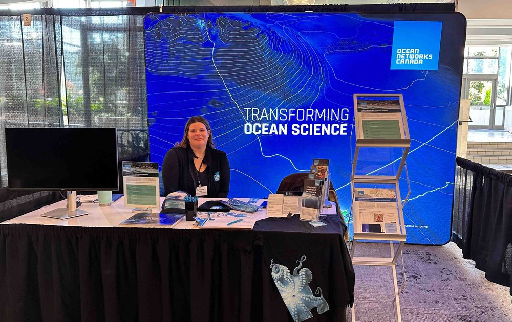 Exhibit booth for Ocean Networks Canada featuring a large blue backdrop with oceanographic map lines and the slogan 'Transforming Ocean Science'.