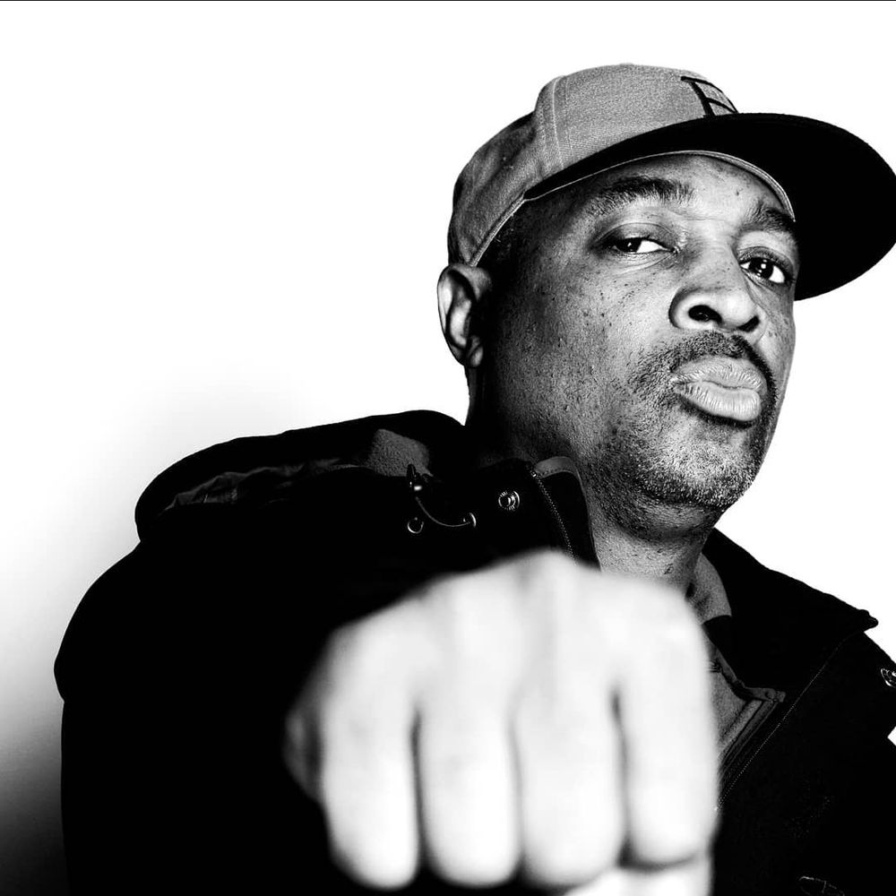 American rapper and founding member of Public Enemy, Chuck D, posing with his fist towards the camera.