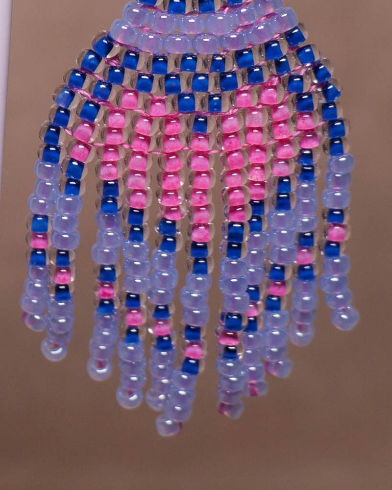 Close-up van handgemaakte oorbel met blauwe, roze en transparante glaskralen als onderdeel van de wintercollectie ‘IJskoningin’.