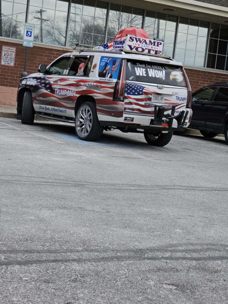 An SUV painted as an American flag and displaying many different symbols of support for Trump 