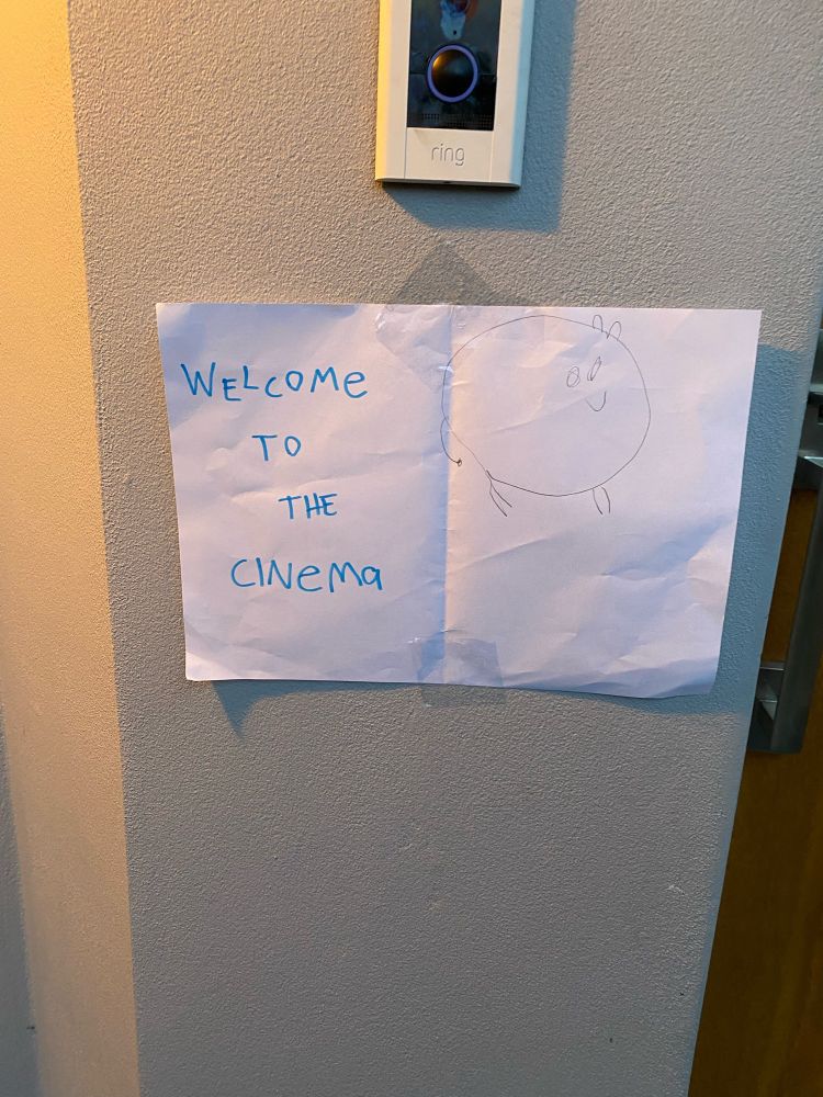 White paper sign outside a front door reading welcome to the cinema.