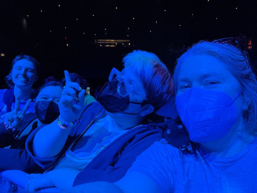 RM3 and three friends in the front row, bathed in blue light 