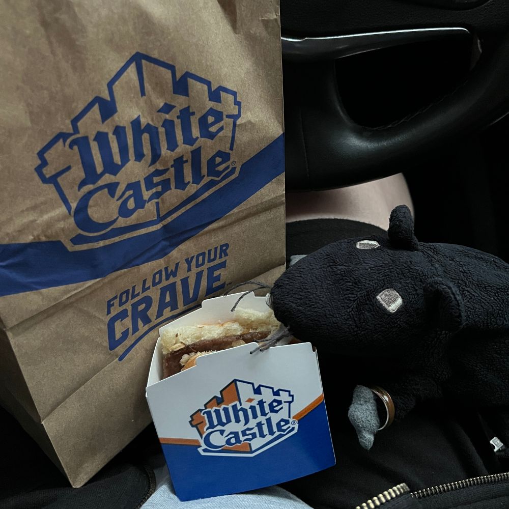 Snap of Zeke sitting on RM3's lap in the car with a bag of White Castle hamburgers. He's got his face in a hamburger box. 