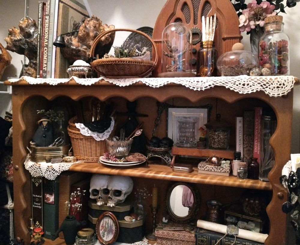 A close up of the top of my hutch in my closet area, which houses many books, baskets, trinkets, crafting items, apothecary items, and tea blending objects