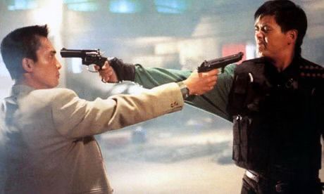 Two men, one in a white suit and the other in tactical gear, point guns at each other.