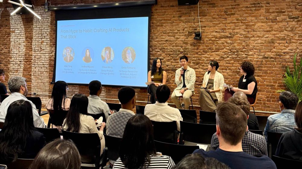 Four people sitting in front of a room with an audience