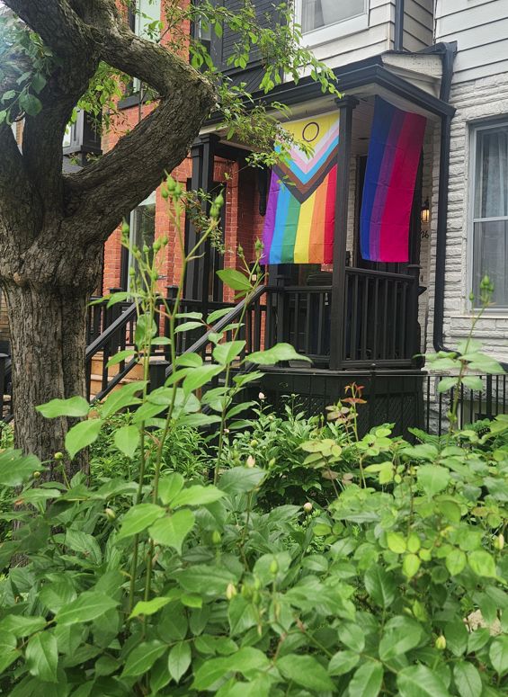Image of a front porch with a pride progress flag and a bi pride flag.