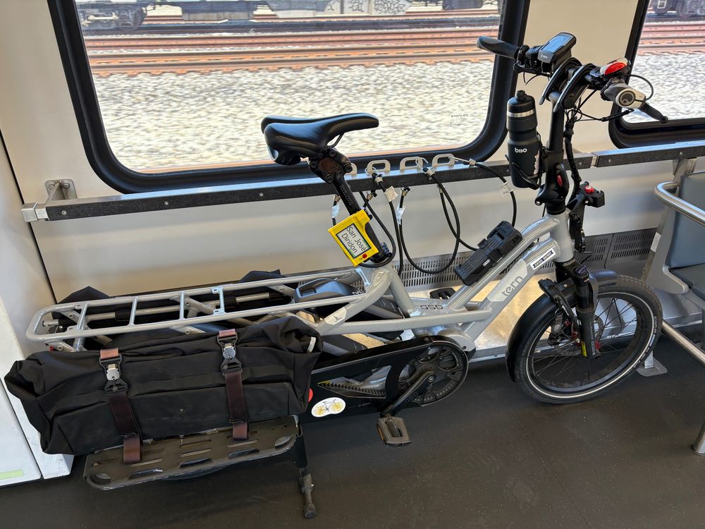 My bike, a gray Tern GSD R14 long-tail cargo e-bike, standing in one of Caltrain's bike cars. The bike has accessories including panniers and a bell with a Canadian flag design. The digital bike tag described earlier in the thread is attached to the seat post.