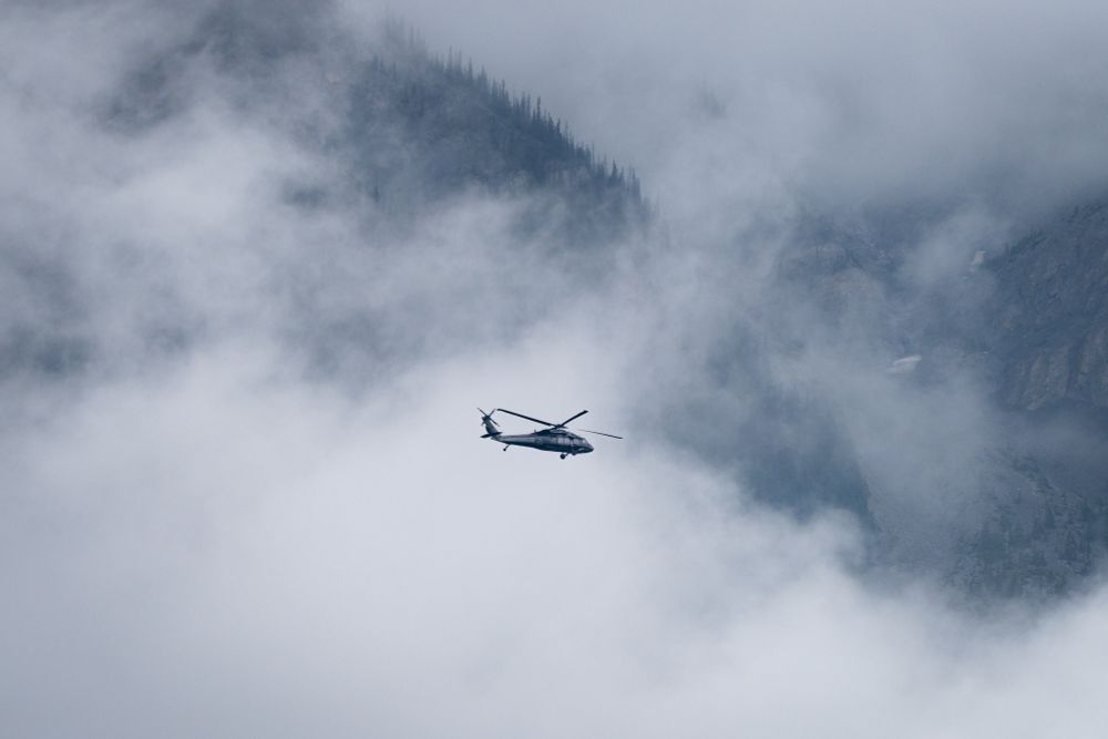 Helicopter flying in front of a cloud covered mountain.