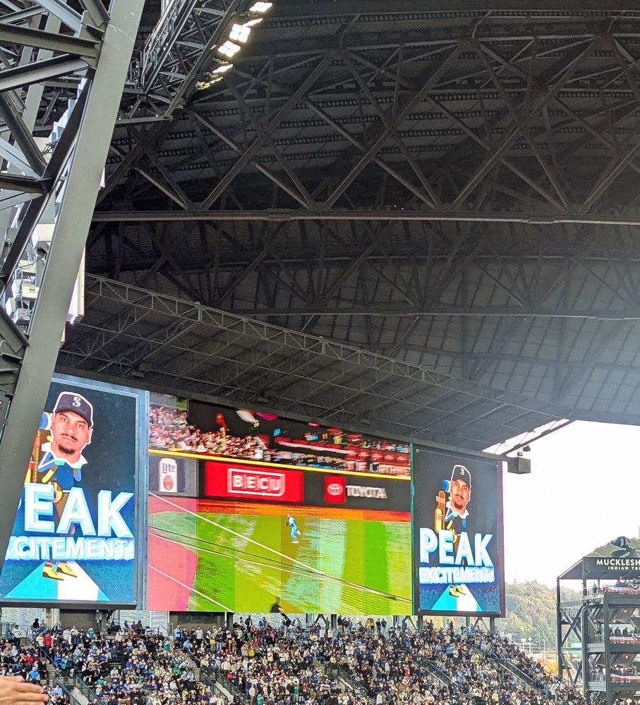 the mariner vision screen after naylor's base hit has a graphic that says PEAK EXCITEMENT . it's clip art of a little hiker guy on a mountain peak with naylor's stone face 
