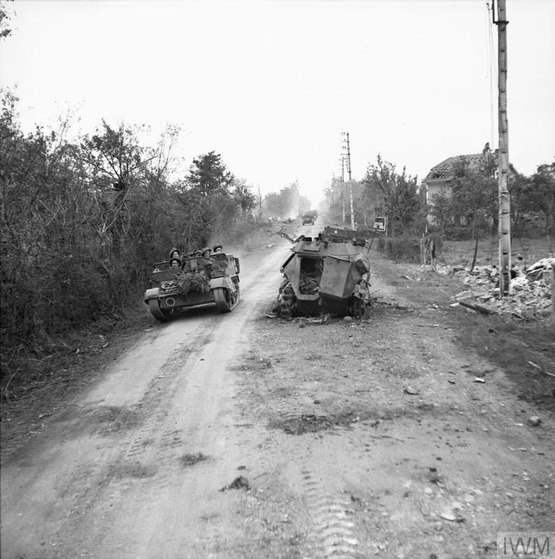 A British carrier drives past a German half-track.