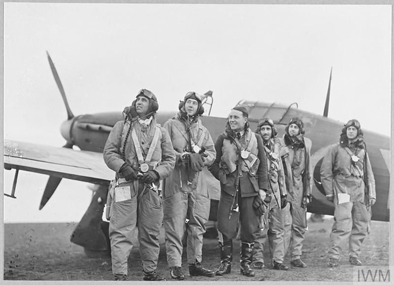 Six in flying kit stand by an aircraft.