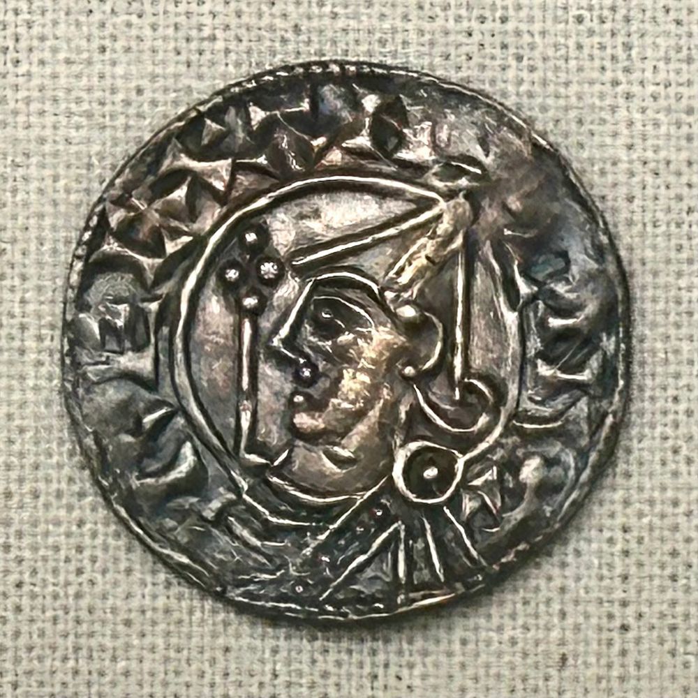 Silver penny coin showing the stylised head of a king, in Barnstaple Museum. My photo.