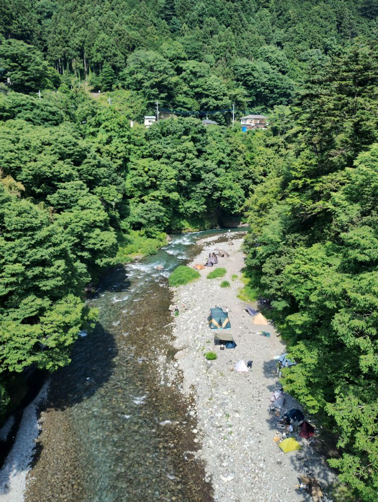 A riverside campsite seen from a bridge.