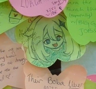 Colourful post it notes in a collage on wall, focusing one with a cute drawing of Paimon on.