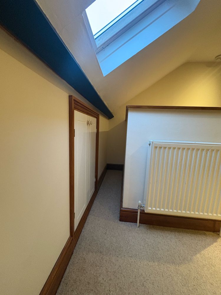 A very narrow flooring between a wall and staircase. 