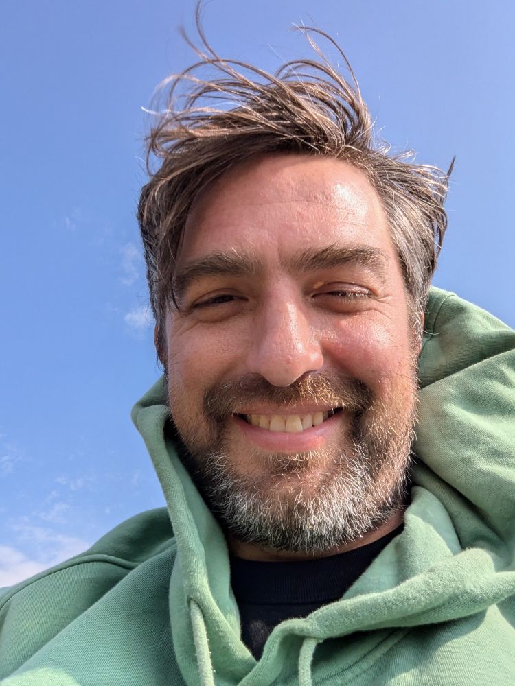 Selfie of me in a green hoodie blown around by the wind but happy