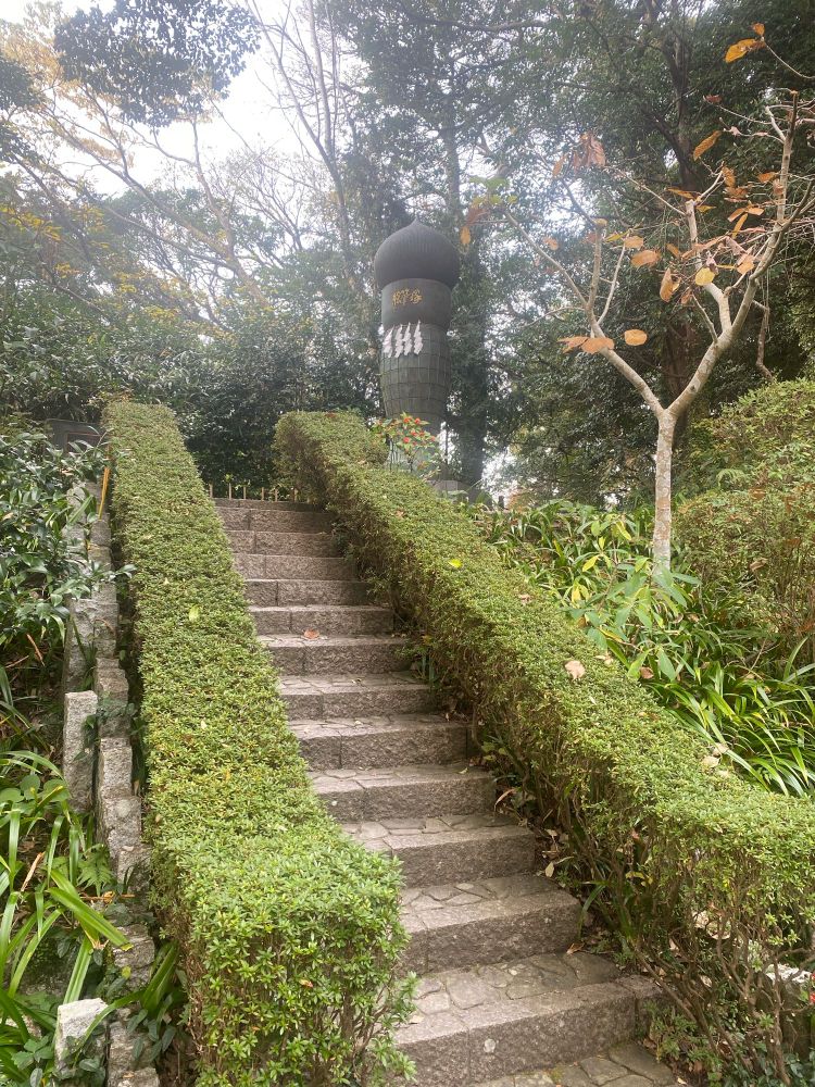 鎌倉の荏柄天神社の写真です。階段の上に、石造りのモニュメントがあります。絵筆塚という名前で、絵筆を模した石の造形物の表面に、数々の著名な漫画家の先生方が寄稿された河童の絵のレリーフが並べられています。漫画にご利益があると有名な神社なのです。