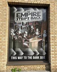 a poster for The Empire Strips Back that says “THIS WAY TO THE DARK SIDE”