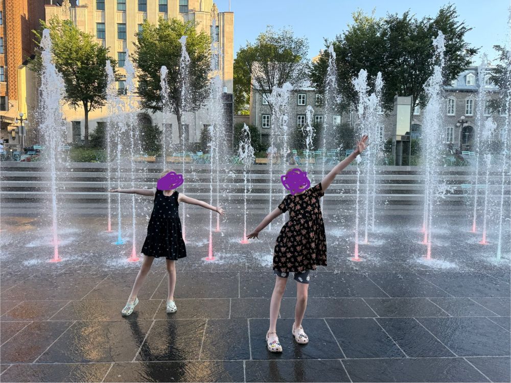 Two kids standing in front of fountains on the street
