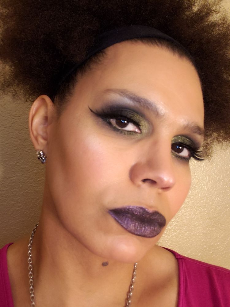 Kaidee wearing a dark smokey eyeshadow blending into gold in the inner eye.  She is also wearing a black lipstick with pink shimmer.

Kaidee is staring into your soul, imploring you to donate.