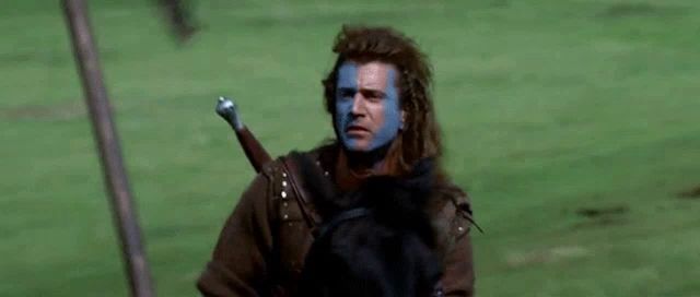 a man with blue paint on his face is riding a horse with a sword .