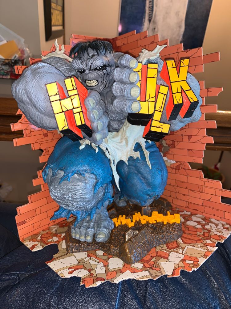 A sculpture of The Incredible Hulk front cover from issue #345 by Todd MacFarlane in 1988. The Grey Hulk is breaking apart the customary "HULK" title for the comic book as the letters of "The Incredible" lie jumbled at his feet.
