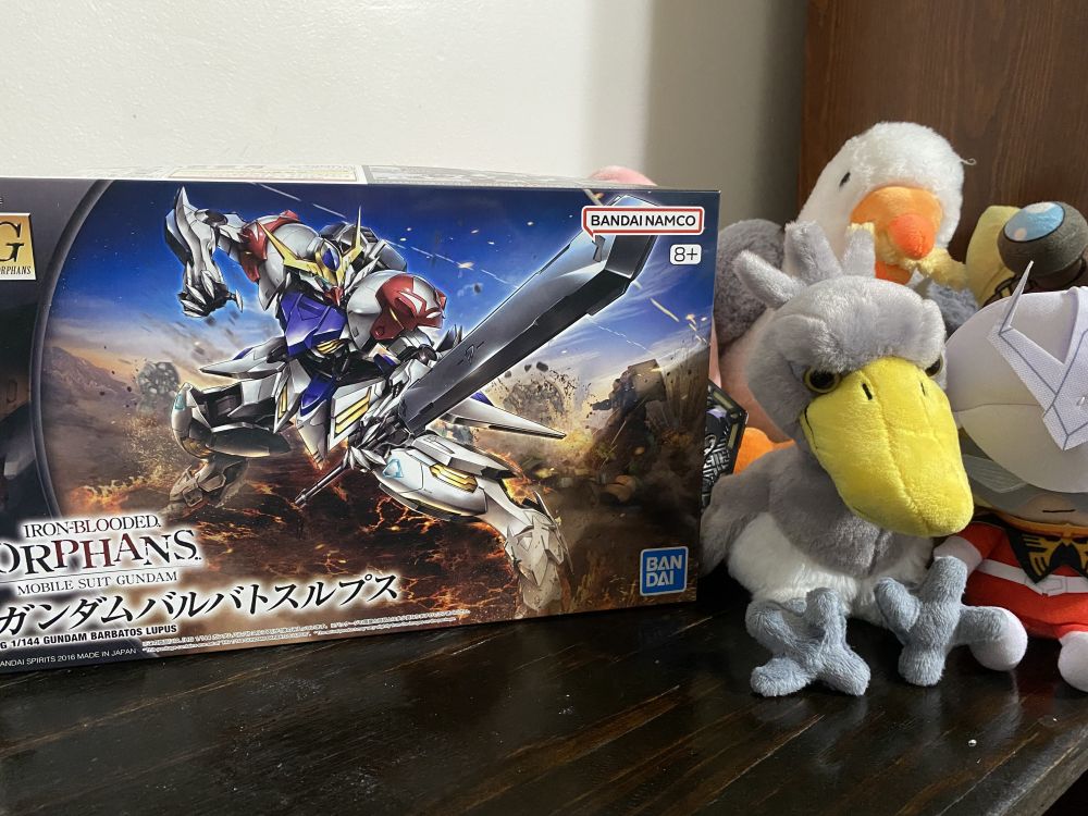 the box for the HG Barbatos Lupus, next to a plushy shoebill and the vile Red Bug