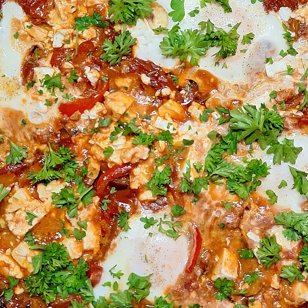 Pfannengericht aus Paprika, Tomaten, Eiern, Petersilie, Schafskäse von oben.