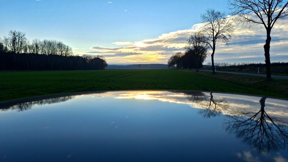 Sonnenuntergang spiegelt sich in glatter Fläche. 
