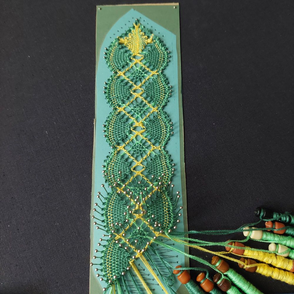 Colourful torchon lace bookmark in shades of green and yellow.   There are minor mistakes which the maker is choosing to embrace as part of her development