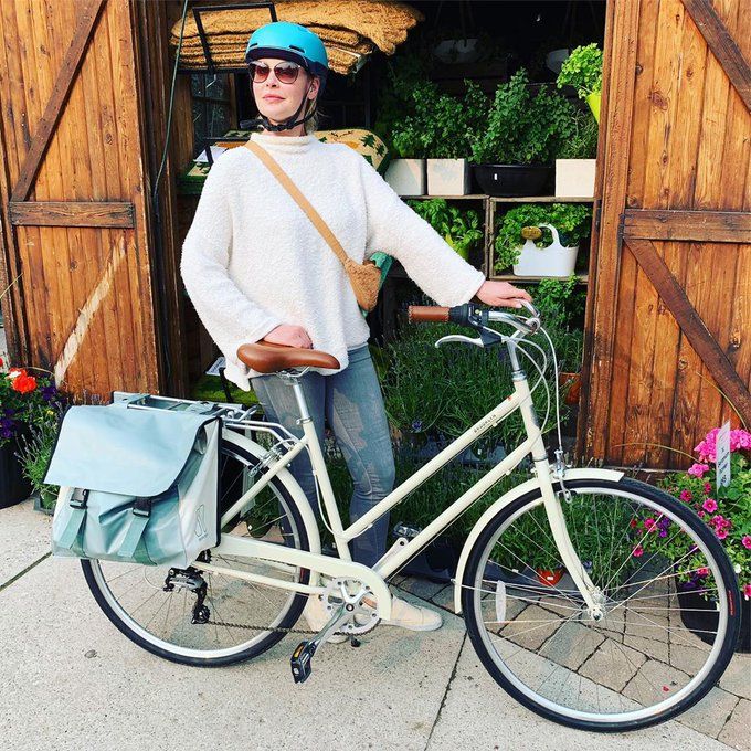 Photo of a woman wearing a turquoise bicycle helmet, sunglasses, and an over-the-shoulder bag posing standing with a bicycle with upright, step-through frame and panniers on the rear rack. She's standing in front of a wooden shed with many plants inside.

The quote and photo were taken from a post Katherine Heigl (the subject) made on Twitter on June 1, 2019.