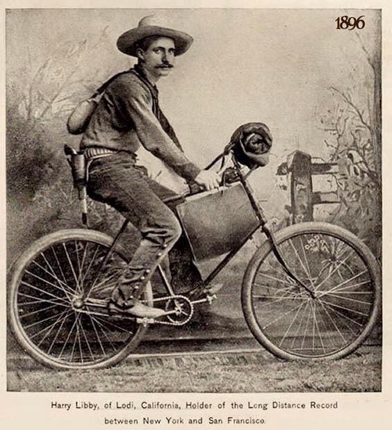 Studio photograph of a man dressed like a cowboy riding a bicycle