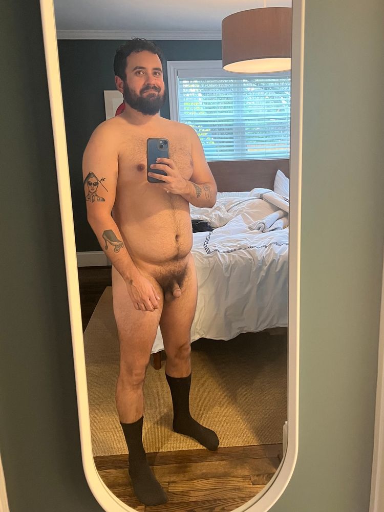 a picture of me naked in my bedroom wearing only black socks with a slight smile and a soft cock 