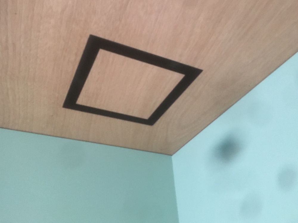 Gaboon plywood ceiling in bathroom with negative detail air extraction grills from Ventech. The square ply cutout is recut to fill the centre leaving a black negative detail for air path, giving continuous grain from ply across the fitting.